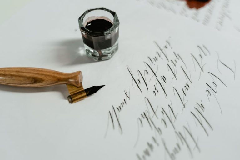 Escritura copperplate con pluma flexible y tinta negra sobre papel satinado