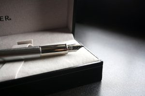 Caja de regalo con pluma estilográfica y frasco de tinta sobre madera