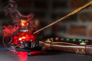 Varita mágica sobre libro abierto con atmósfera oscura, réplica oficial Harry Potter