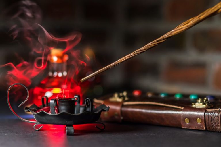 Varita mágica sobre libro abierto con atmósfera oscura, réplica oficial Harry Potter