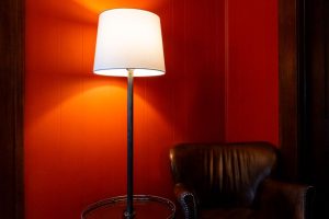 Lámpara de pie vintage con trípode de madera en rincón de lectura de salón decorado en estilo retro