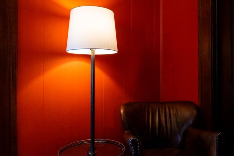 Lámpara de pie vintage con trípode de madera en rincón de lectura de salón decorado en estilo retro