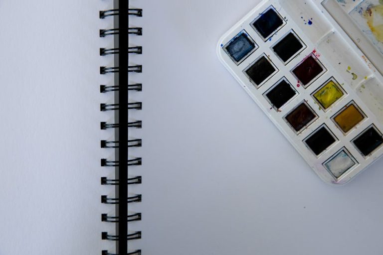 Cuaderno pequeño artesanal abierto con bocetos creativos sobre mesa de artista