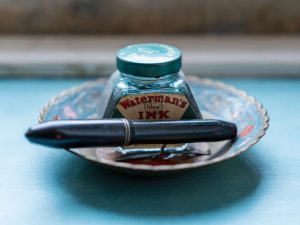 Colección de instrumentos de escritura antiguos: plumas, tinteros y lapiceros sobre terciopelo oscuro