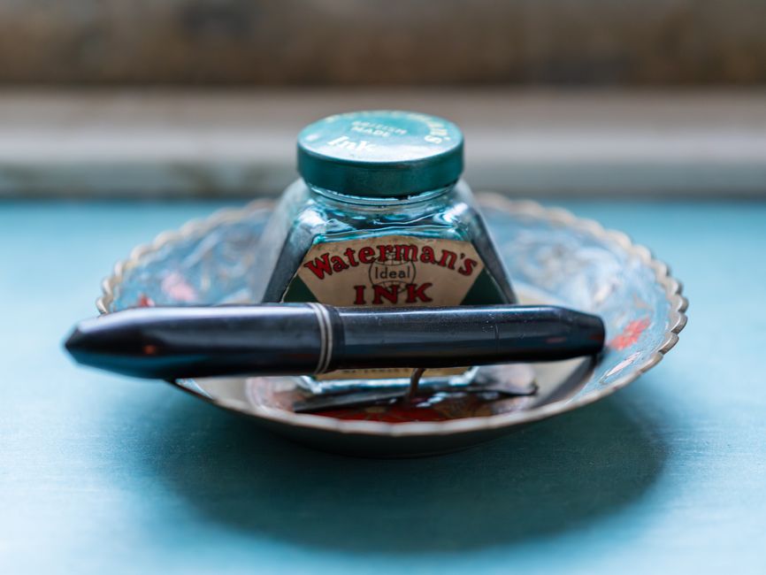 Colección de instrumentos de escritura antiguos: plumas, tinteros y lapiceros sobre terciopelo oscuro