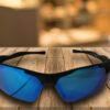Gafas de sol deportivas negras con lente azul espejo, estilo envolvente